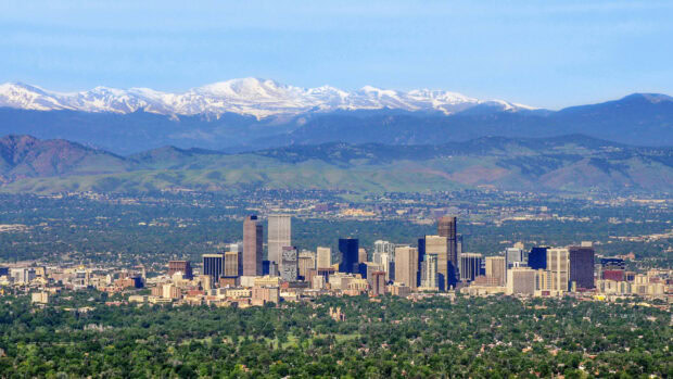 The Denver cityscape with mountain range and green hills in Colorado