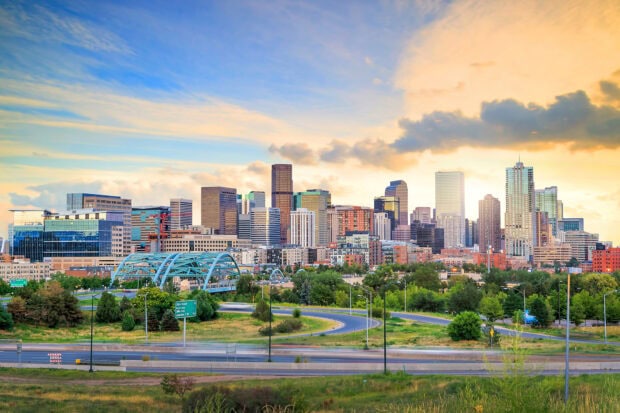 A vibrant view of Denver Colorado city skyline with modern buildings and greenery at sunset