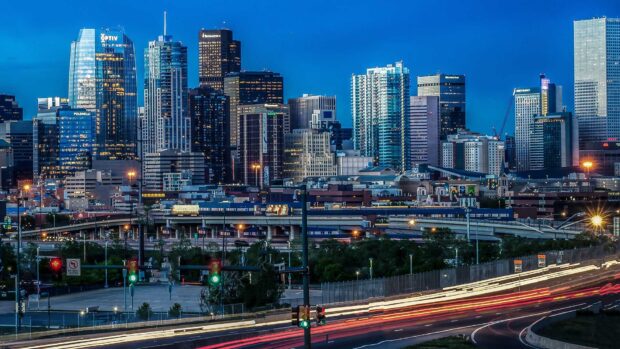 Evening cityscape of Denver Colorado with illuminated buildings and busy traffic at dusk