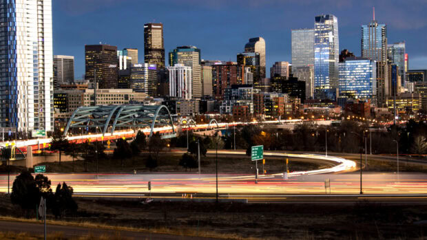 Denver cityscape with downtown skyscrapers and light trails on highways during dusk