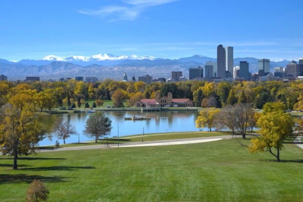 A scenic view of Denver Colorado with a city skyline and mountains in the background