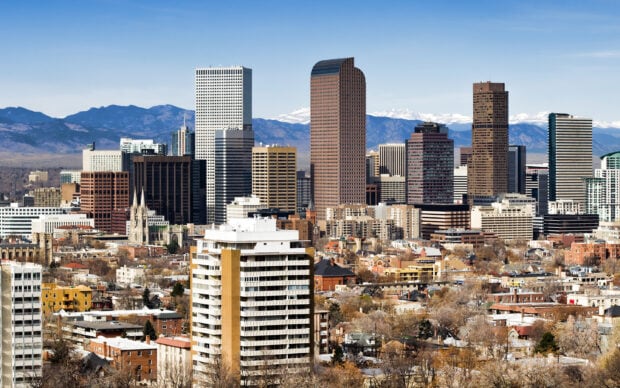 Denver skyline with modern buildings and snowy mountains in the background