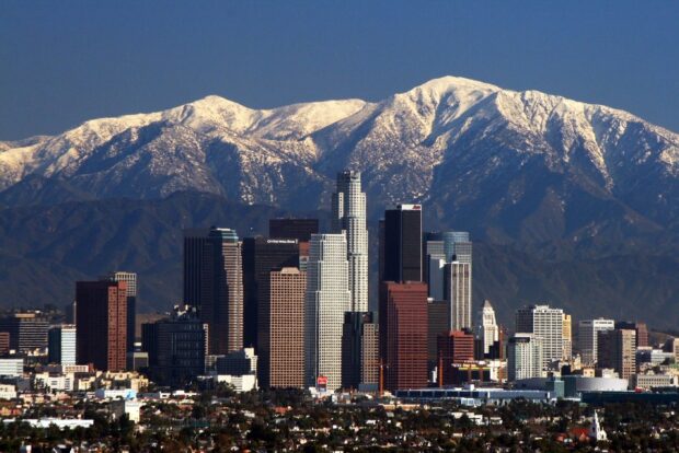 Snow capped mountains behind a city skyline in Denver with clear blue sky