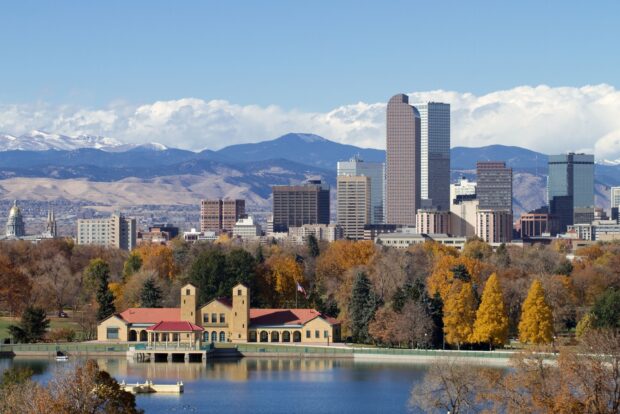 A scenic view of Denver skyline with autumn trees and mountains in the background
