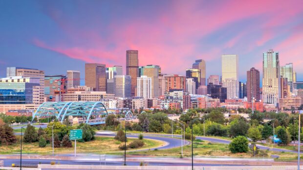 A clear view of Denver skyline with buildings and a blue bridge at sunset sky