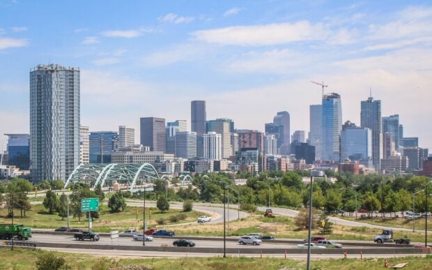 A clear view of the Denver skyline with modern buildings and green spaces under a blue sky