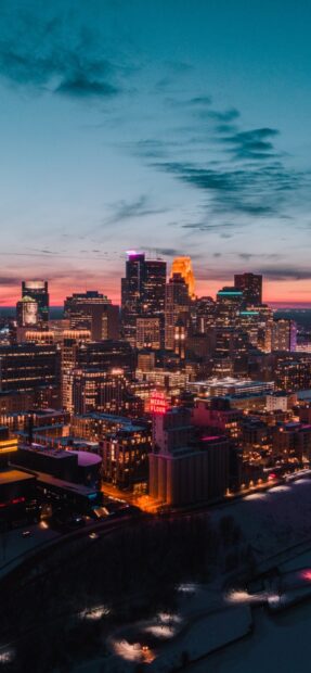 Evening cityscape showing Denver skyline with vibrant lights and colorful sunset sky