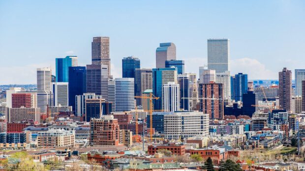 Denver skyline with tall buildings and cranes in a clear blue sky background