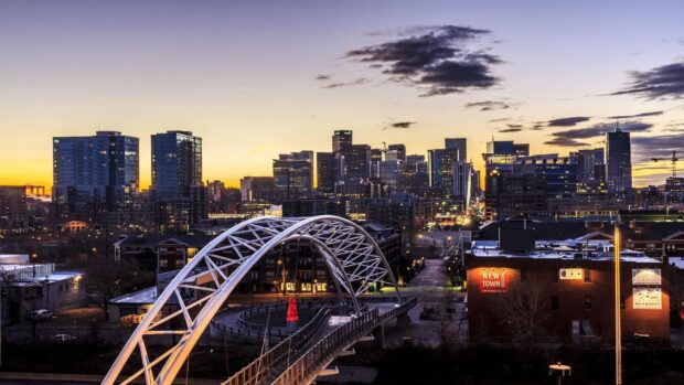 Denver skyline seen at sunset with an illuminated cityscape and modern bridge structure