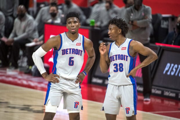 Two Detroit Pistons players discussing game strategy on the court during a timeout
