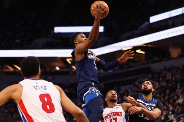 A Detroit Pistons player attempts a shot while being defended by Minnesota Timberwolves players in a basketball game