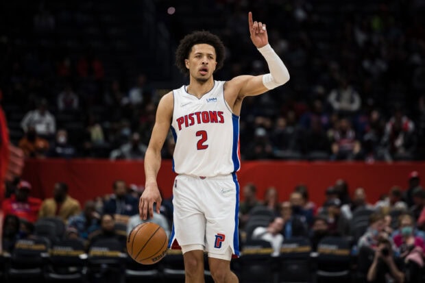 A Detroit Pistons player dribbling the ball during a basketball game in a white uniform