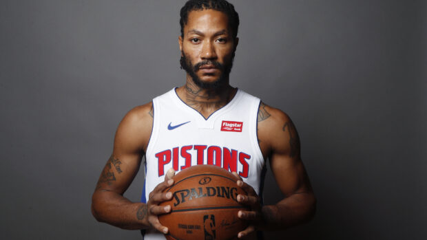 Detroit Pistons player holding a basketball in a white jersey against gray background
