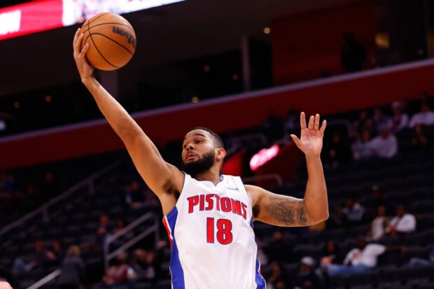 A Detroit Pistons player reaching for a basketball during a game in an arena