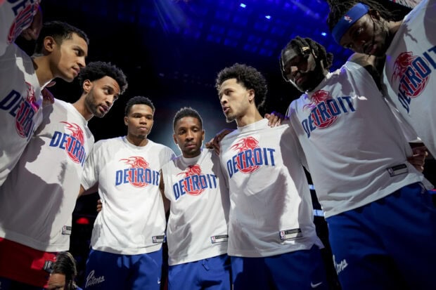 Detroit basketball players wearing Detroit shirts in a team huddle before the game