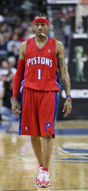 A Detroit Pistons player wearing a red uniform with tattoos and a red headband on the basketball court