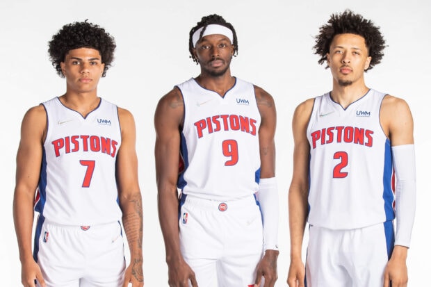Three Detroit Pistons basketball players standing side by side in white uniforms
