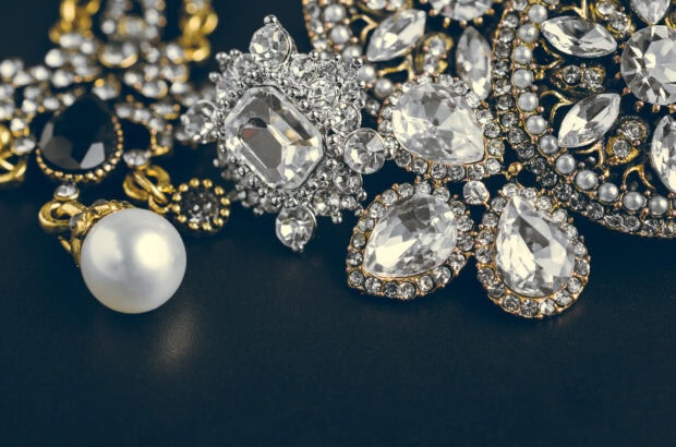 Close up of diamond jewelry with gold and pearl accents on dark surface