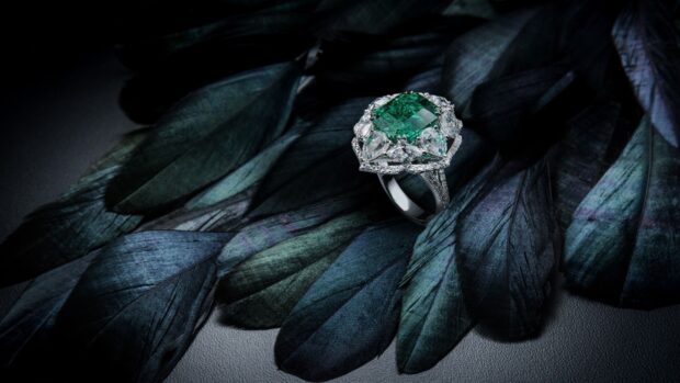 Emerald center diamond jewelry ring on blue feathers