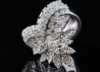 A close up of diamond jewelry with intricate leaf shaped design on a black surface