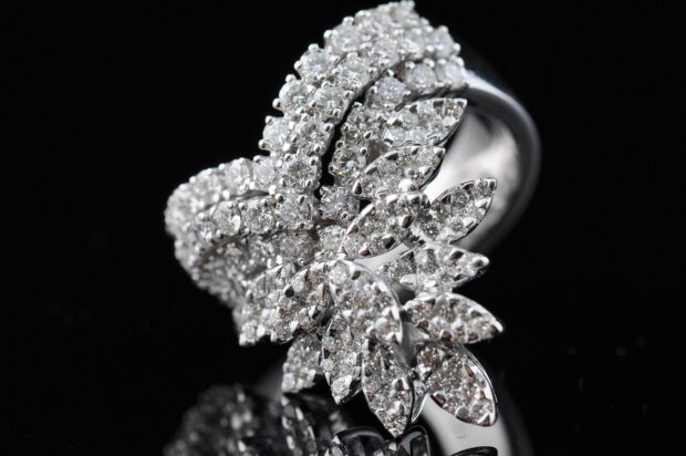 A close up of diamond jewelry with intricate leaf shaped design on a black surface