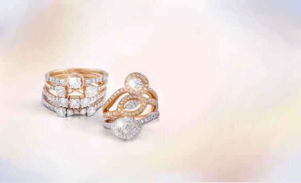 Elegant diamond jewelry displayed in gold settings on a soft pastel background