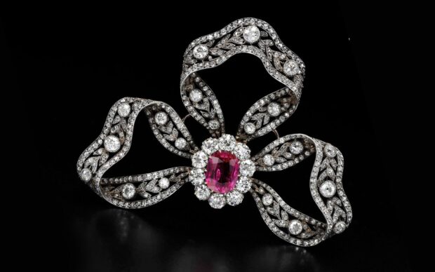 Vintage diamond jewelry with a ruby center and intricate design on black background