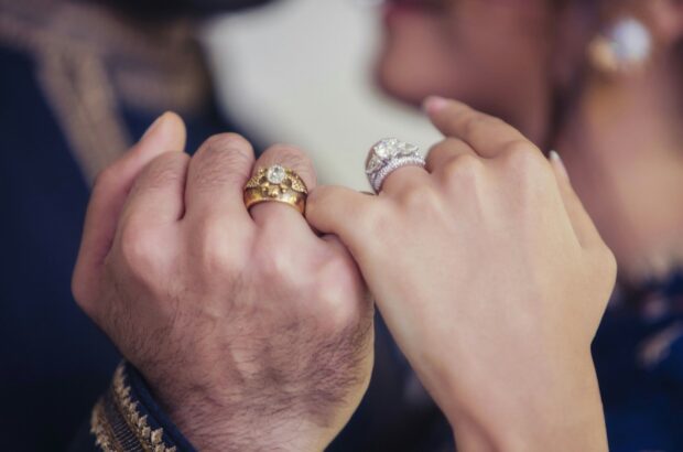 A close up of hands wearing diamond jewelry rings symbolizing love and commitment