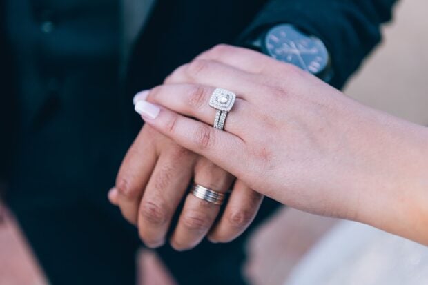 Close up of diamond jewelry on hands showing engagement rings and wedding bands