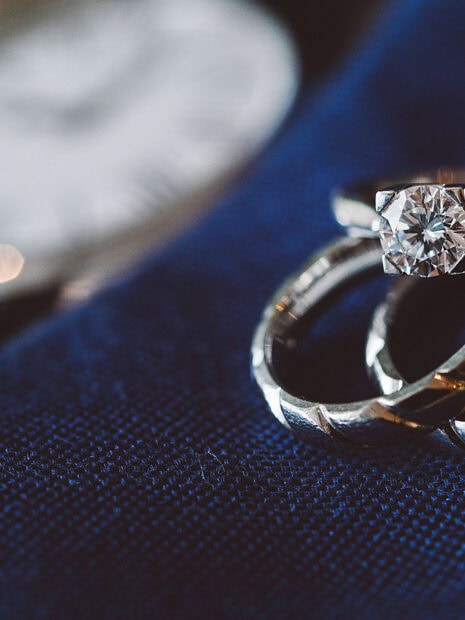 A close up of diamond jewelry rings on a textured blue surface