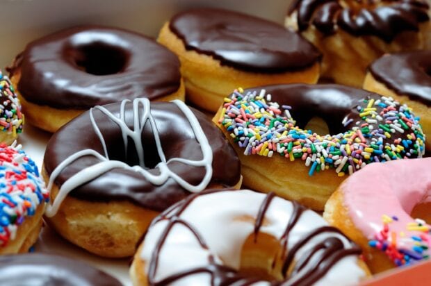 A variety of donut with chocolate and colorful sprinkles topping in a close up view