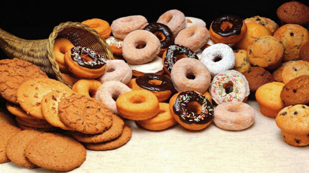A variety of donut pastries surrounded by a basket with delicious donut treats
