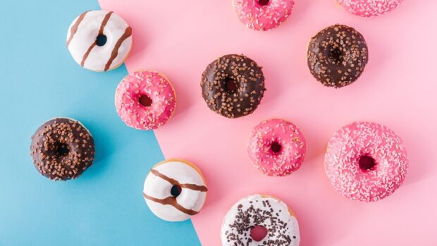 Colorful donuts with various toppings arranged on a blue and pink surface
