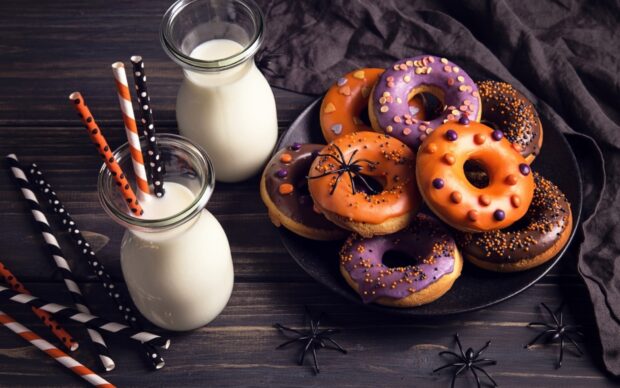 Halloween themed donuts with colorful icing and milk bottles on a wooden table