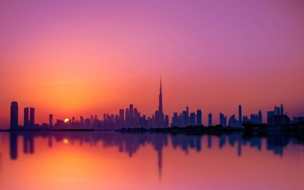 Dubai skyline at sunset with orange and purple sky reflecting on the water