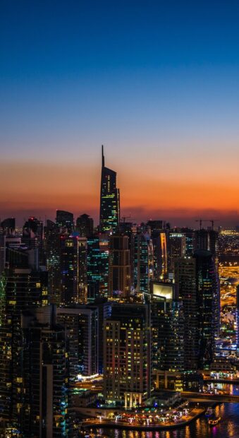 Dubai city skyline at sunset features towering skyscrapers and vibrant lights at dusk