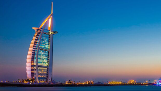 Dubai skyline featuring the iconic Burj Al Arab at dusk with clear skies and city lights