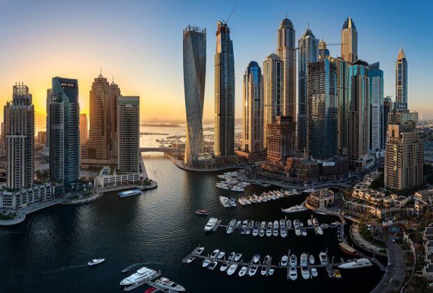 Dubai skyline with modern skyscrapers and yachts in the marina at sunset