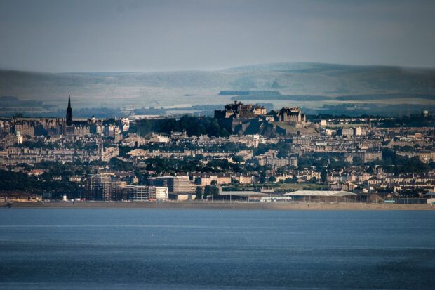 A panoramic view of Edinburgh castle and cityscape with hills in the background