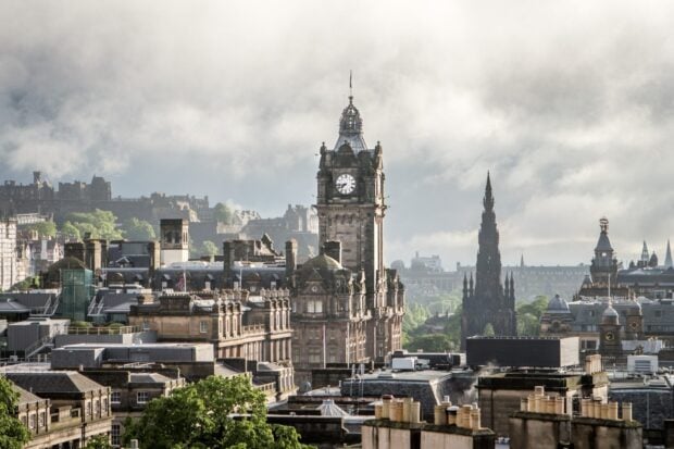 Historic clock tower in Edinburgh skyline with clear sky and cityscape in the background