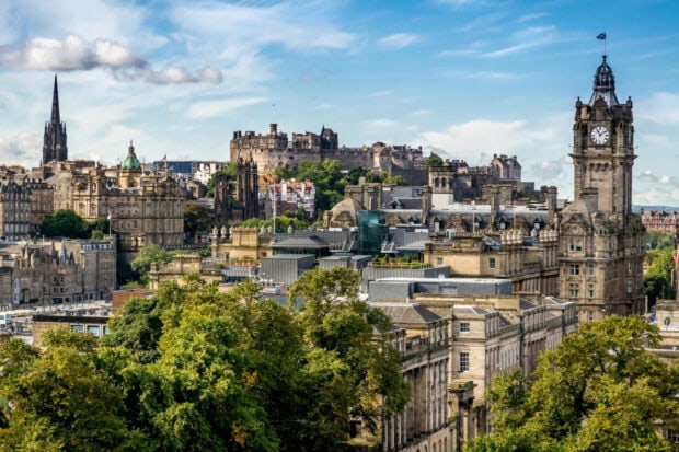 Historic Edinburgh skyline featuring iconic castles and buildings surrounded by lush green trees
