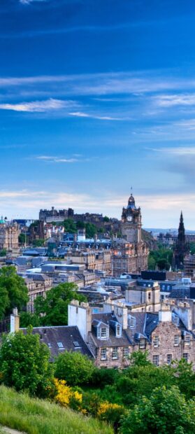 Historic Edinburgh skyline with iconic buildings and lush greenery at sunset