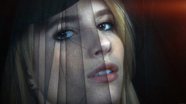 A close up of Emma Roberts face partially covered with sheer black fabric