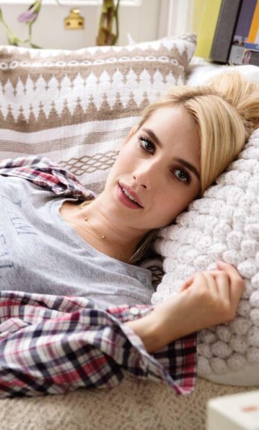 Relaxed Emma Roberts lying on a cozy pillow with a plaid shirt