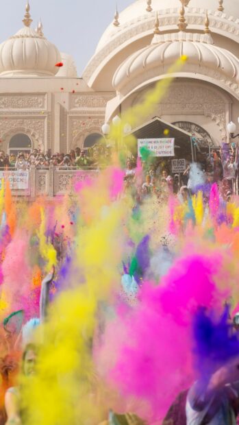 People celebrating with colorful powder during festival celebration in front of temple