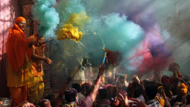 Person celebrating festival with colored smoke in a crowded festival scene