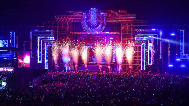Bright lights and fireworks at a large music festival crowd during a festival celebration