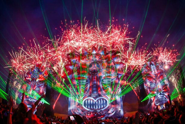 Colorful festival stage with vibrant masks fireworks and green laser lights at night festival