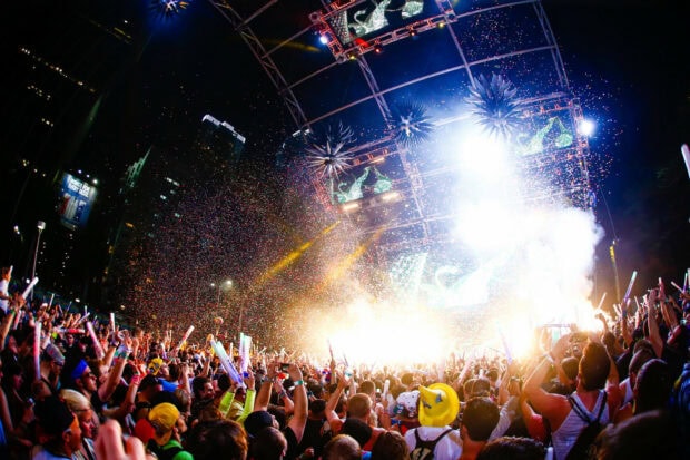 A vibrant festival crowd enjoying a night concert with colorful confetti and bright lights