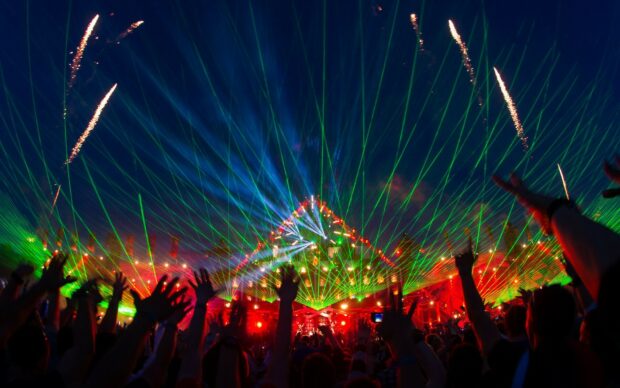 A vibrant festival crowd enjoying laser lights and fireworks at night celebration